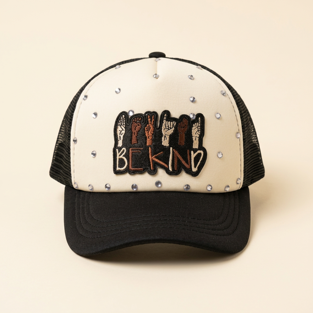 Kindness Speaks black and cream trucker hat with BE KIND hand-sign patch and silver rhinestones on a cream background