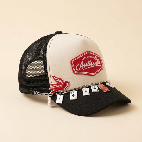 Side view of In My Original Era black and cream hat showing the single red bird patch and card charm chain on a cream background