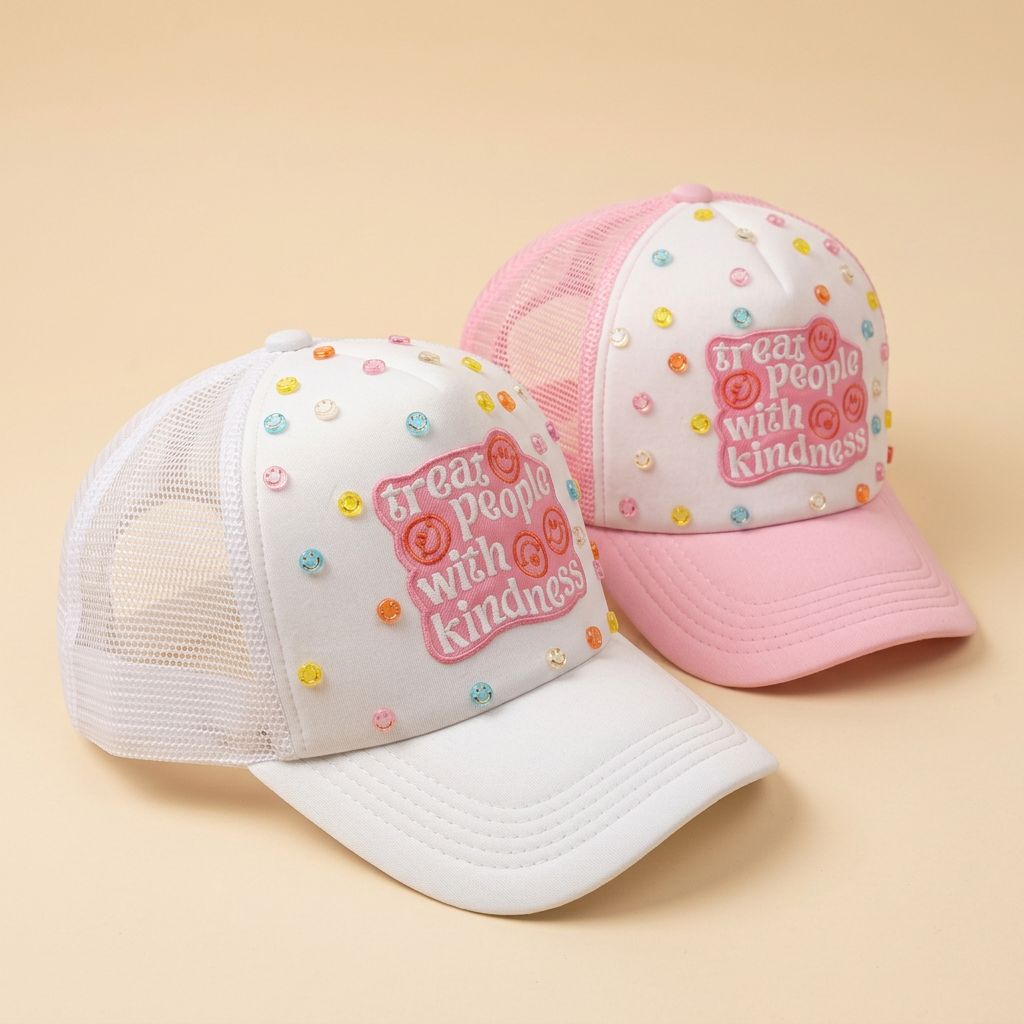 Angled side view of matching pink and white Kindness N Sunshine hats on a cream background